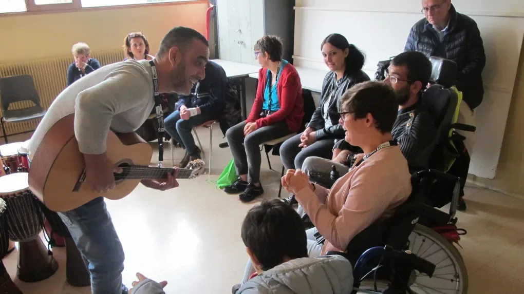 Lahouari Bouregaya, guitare à la main, anime un atelier avec un groupe